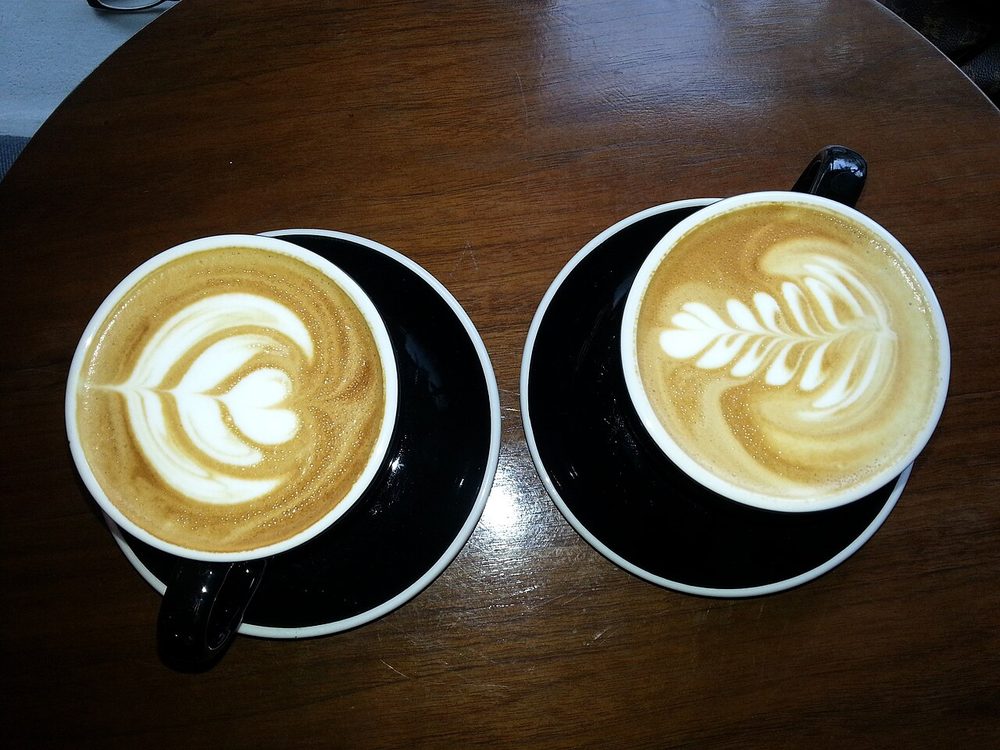 Two cups of coffee with latte art on a wooden table